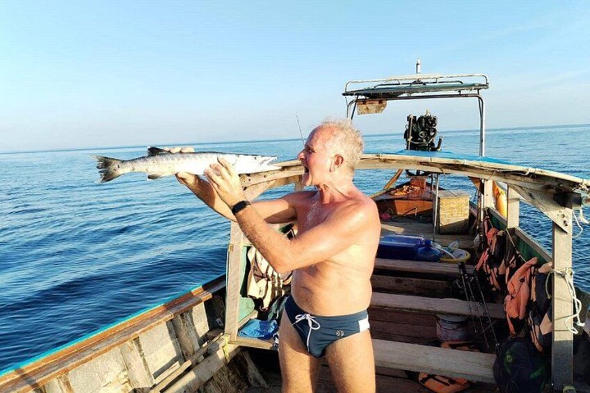 En person på en båd holder en fisk. 4