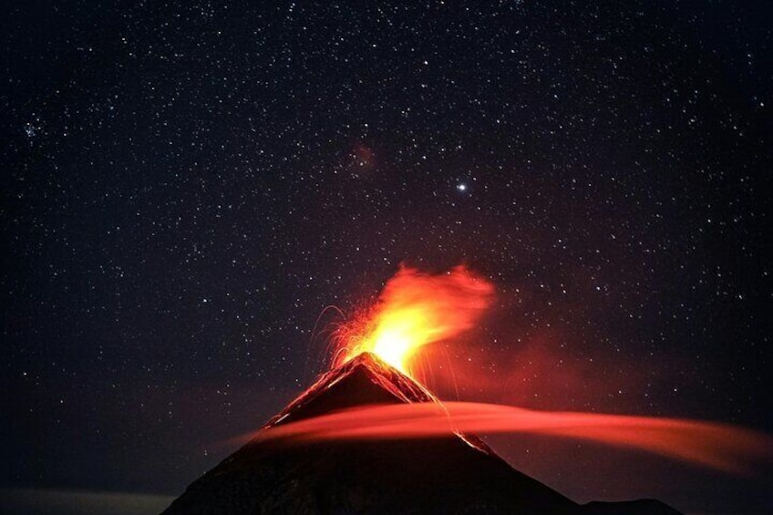 A volcano erupting at night with a bright lava flow. 1