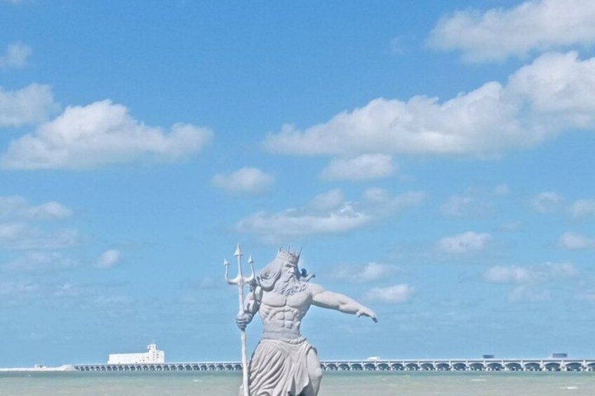 Une statue représentant une figure tenant un trident, avec une jetée et un navire en arrière-plan. 4