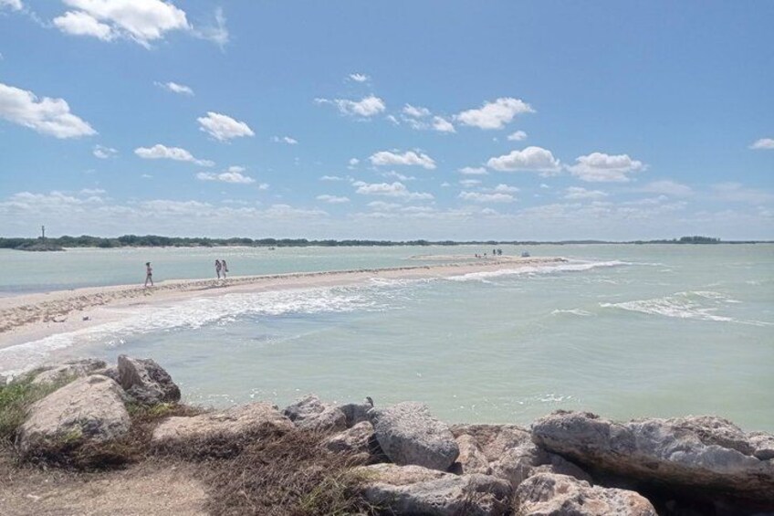 Une plage avec une eau claire, des rochers et une côte qui s’étend au loin. 3