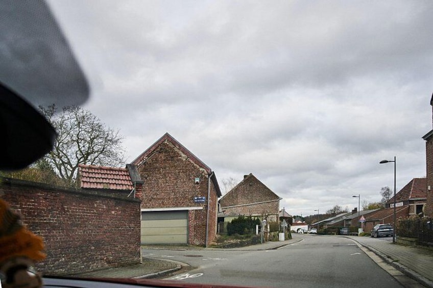 A quiet street with brick buildings, a car, and a pedestrian crossing. 3