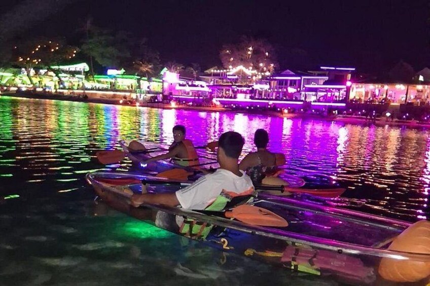 People on a boat with colorful lights reflecting on the water at night. 3