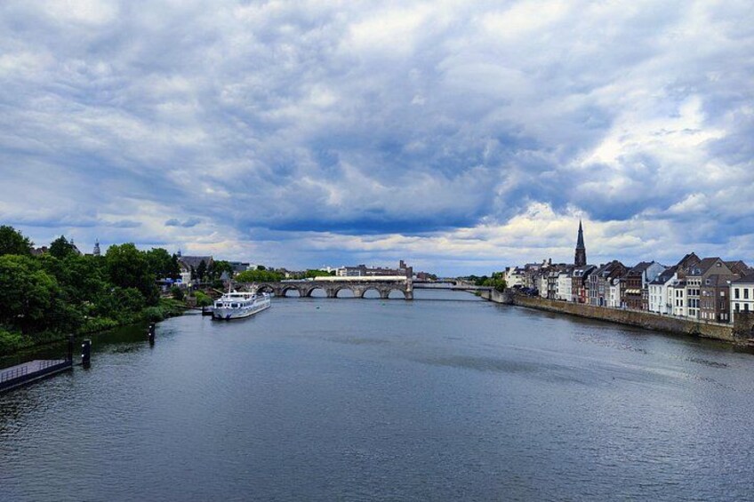 A river with a bridge, a boat, and buildings along the banks. 1