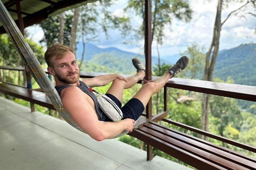 A person reclining on a hammock in a natural setting with a view of a mountainous landscape. 2