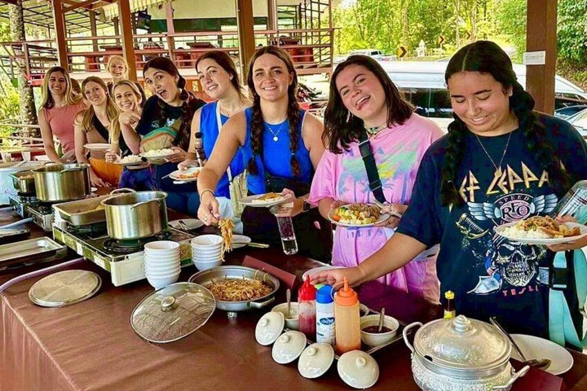 A group of people serving themselves food at a buffet table with various dishes and condiments. 3