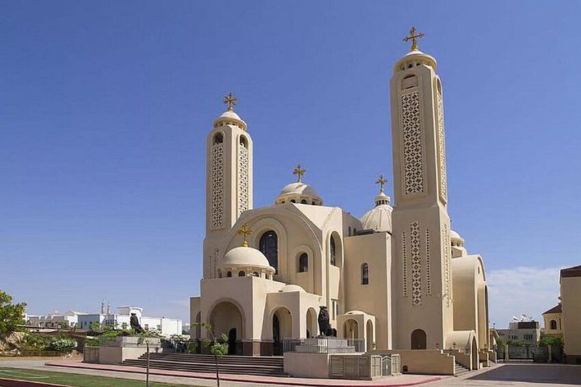 A large beige church with two tall towers and a central dome, surrounded by a clear blue sky. 3