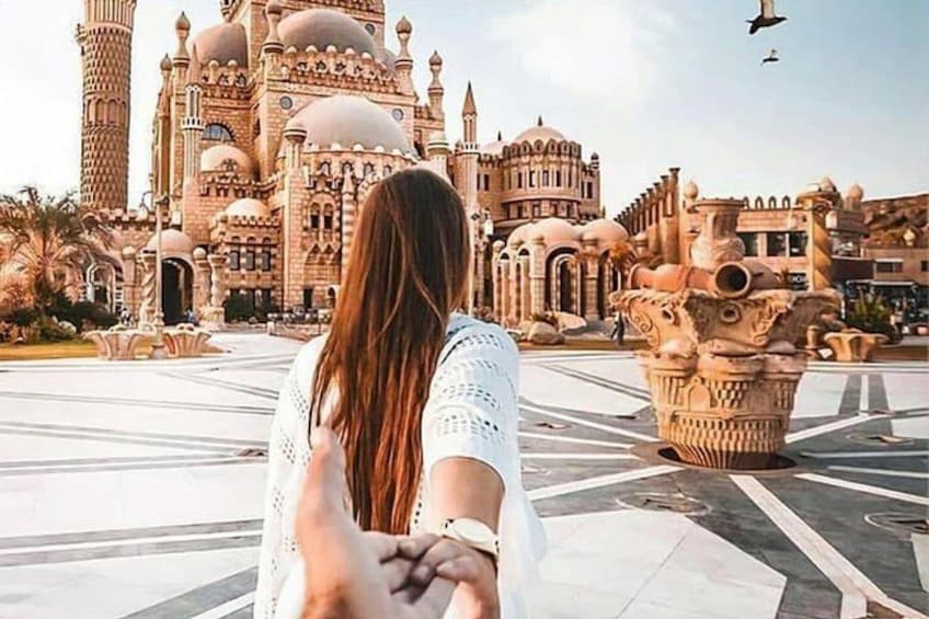 A person standing in a plaza with a large, ornate building in the background. 2