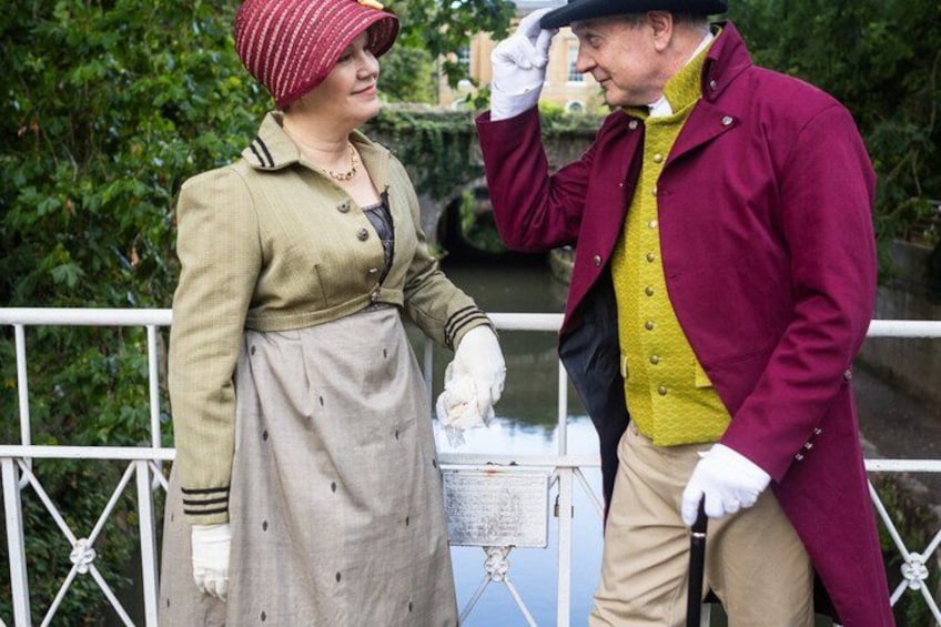 Two people in historical costumes standing near a water feature. 5