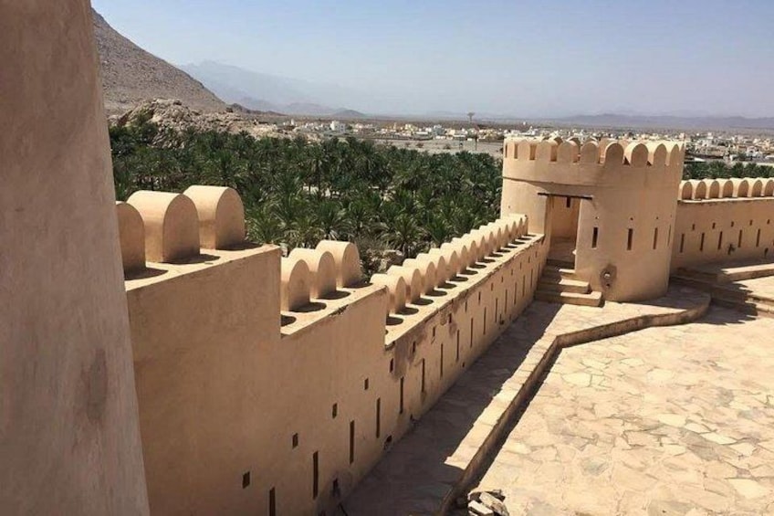 A fortified structure with arched towers and a clear view of a distant cityscape. 3