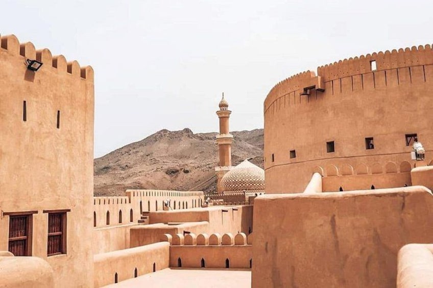 A fortified structure with a minaret and a dome, surrounded by a desert landscape. 1