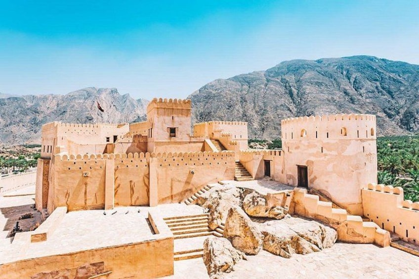 A historical fort with a staircase leading to the entrance, set against a mountainous backdrop. 2