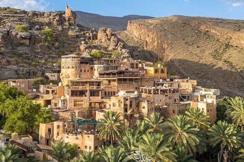 A mountainous village with traditional architecture, palm trees, and rocky terrain. 5