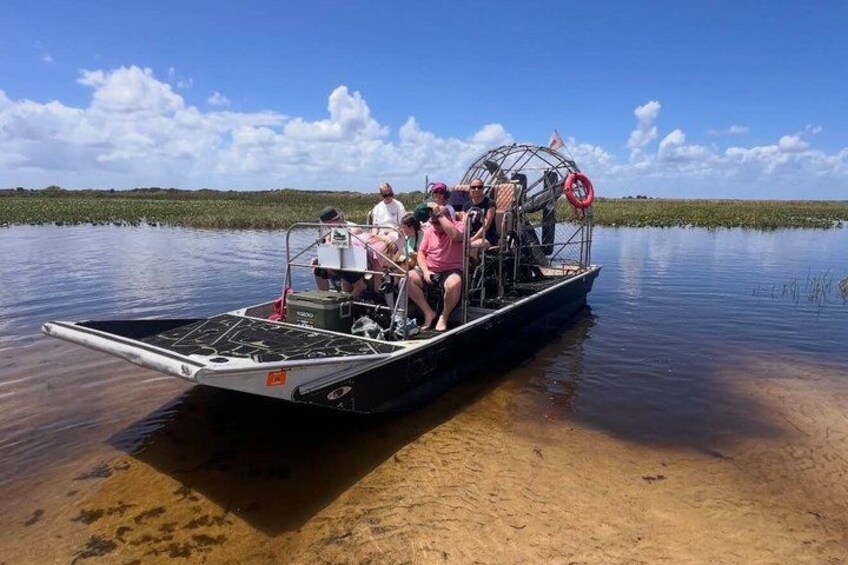 Un bote con pasajeros sobre aguas tranquilas, rodeado de vegetación. 2