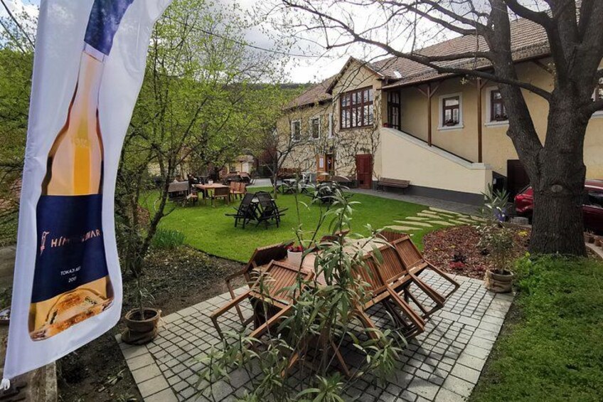 A garden with a table and chairs, a flag, and a house in the background. 4