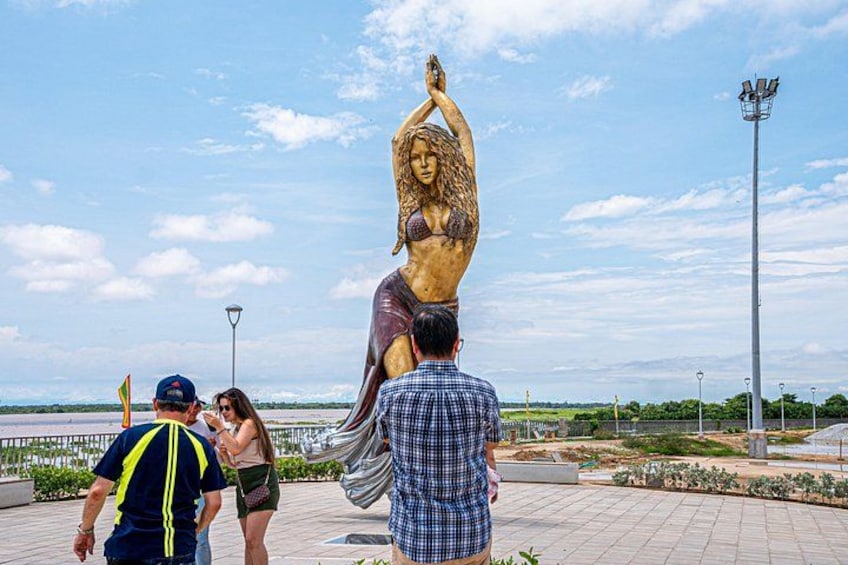 A large statue of a woman in a bikini, surrounded by people. 4