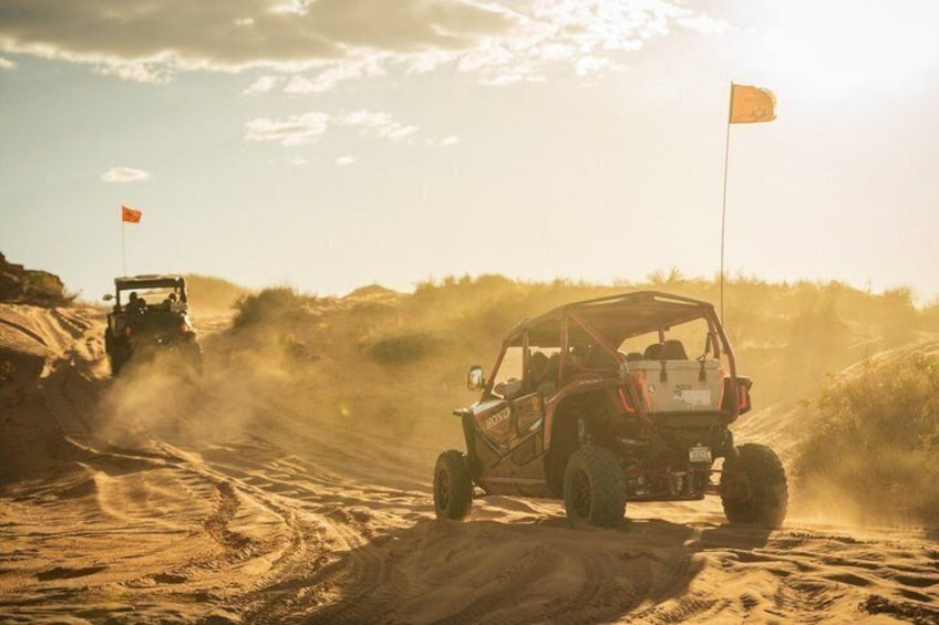 A desert off-road vehicle driving on a sandy path with flags. 1