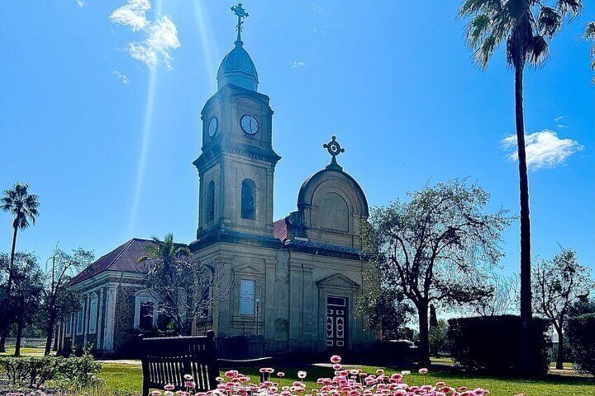 Une église dotée d’un clocher, entourée de palmiers et de fleurs. 3