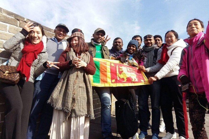 A group of people holding a flag with a lion emblem, standing in front of a brick wall. 2