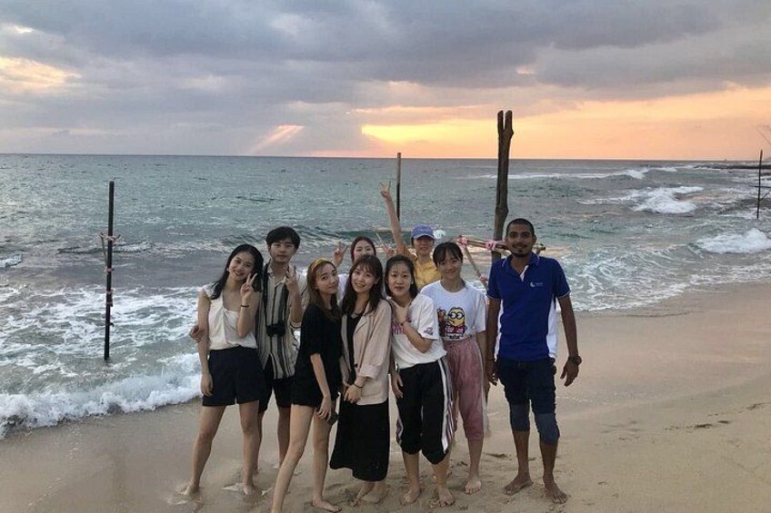 A group of people on a beach with the ocean and a sunset in the background. 5