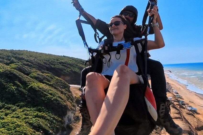 Deux personnes sur une tyrolienne, avec une plage et l’océan en arrière-plan. 2
