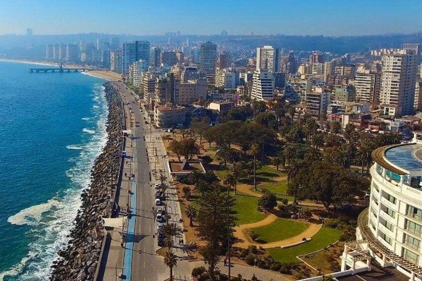 A coastal cityscape with a long beachfront, high-rise buildings, and a park area. 1