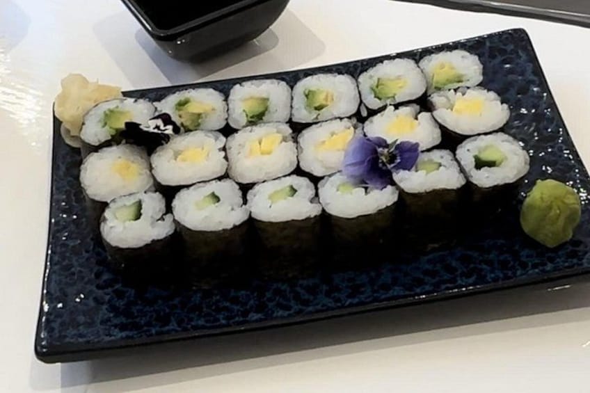 A plate of sushi with a decorative flower and wasabi. 3