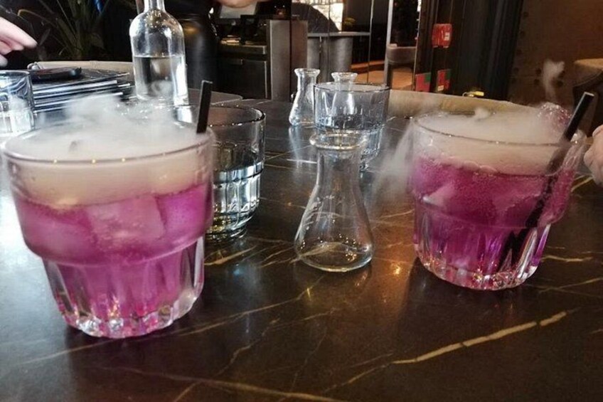 Two glasses of a purple drink with ice cubes on a bar counter. 2