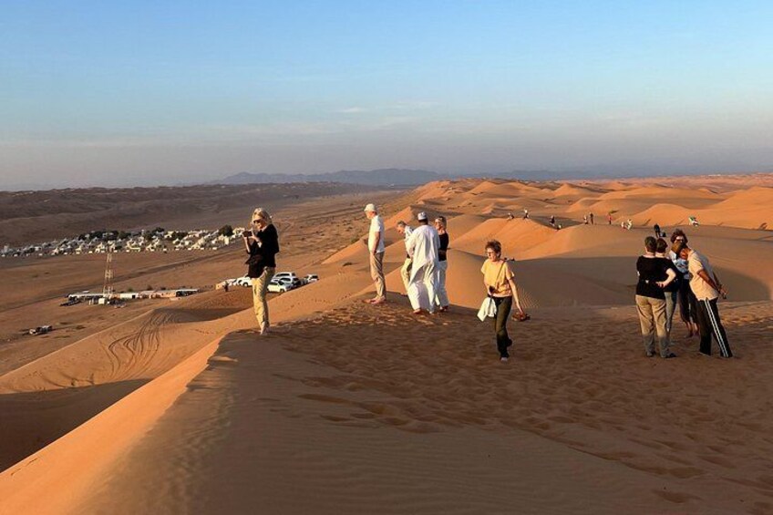 A group of people walking on sand dunes in a desert landscape. 4
