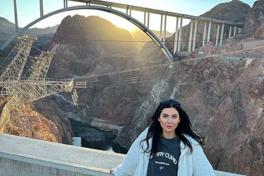A person standing near a bridge with a mountainous landscape in the background. 1