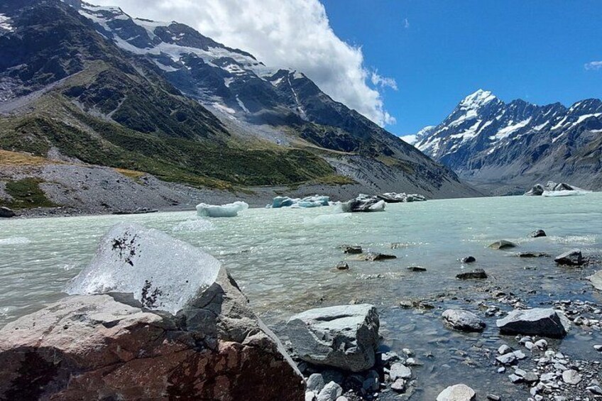 Une rivière glaciaire parsemée d’icebergs, avec un paysage rocheux et des montagnes aux sommets enneigés. 5
