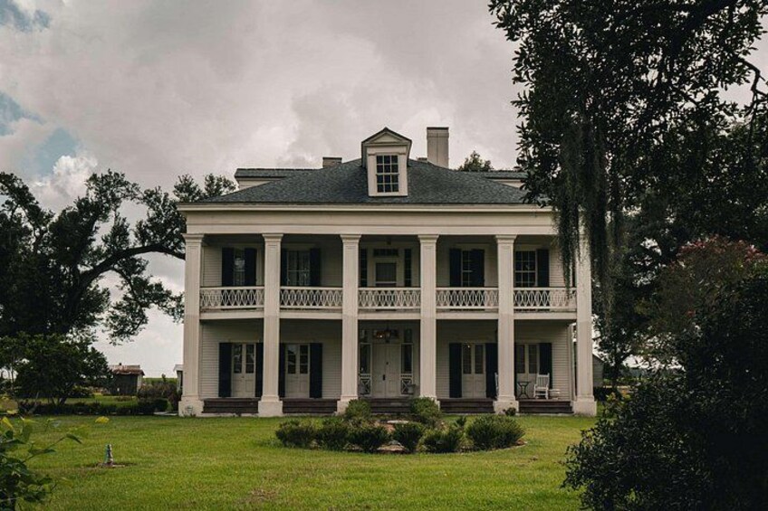 A large, two-story white house with a central balcony and a symmetrical facade. 3