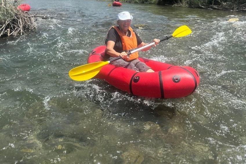 A person kayaking in a red raft on a river. 3