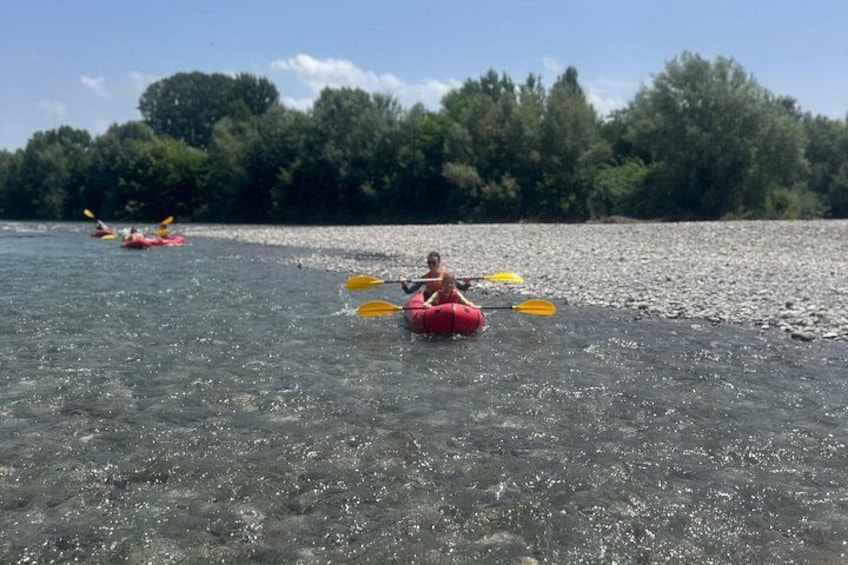 A person kayaking on a clear river with trees in the background. 4