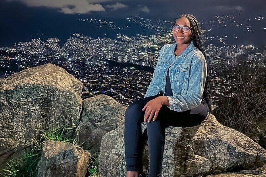 A person sitting on a rock with a cityscape in the background. 4