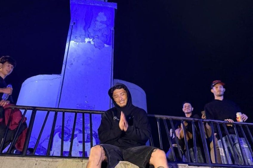 A person sitting on a metal railing with a large blue sculpture in the background. 4