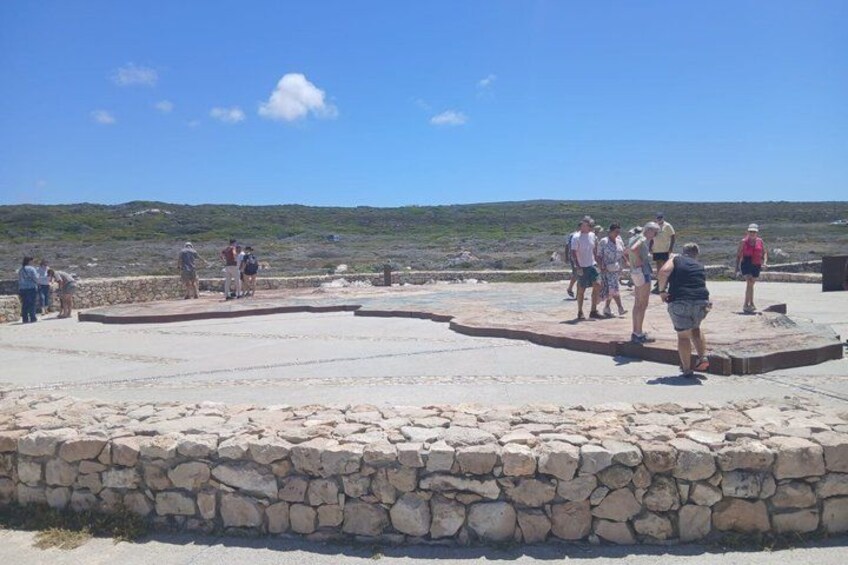 A stone-paved area with people standing and walking around. 4