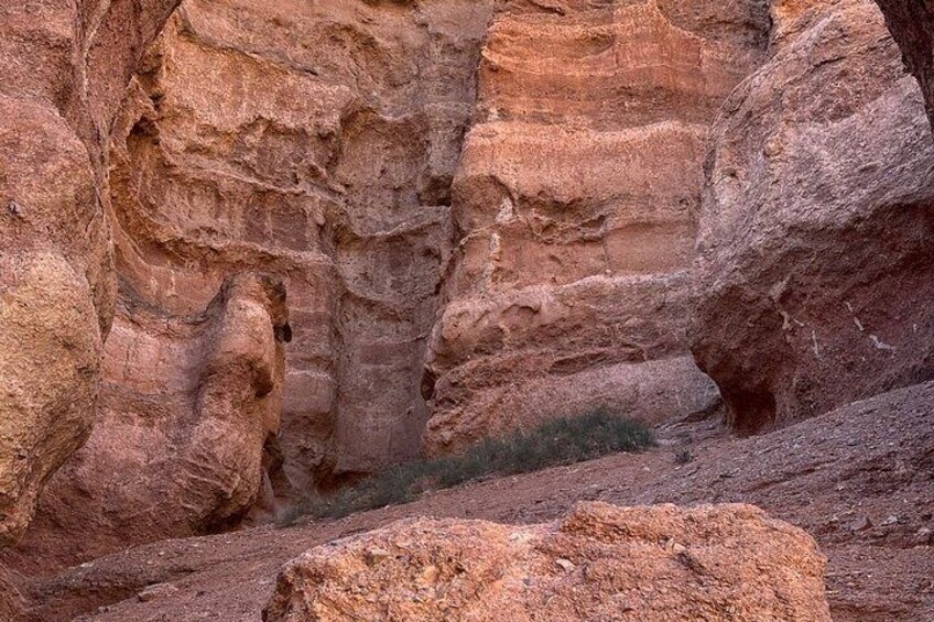 Een canyon met gelaagde rotsformaties en een beekje. 1
