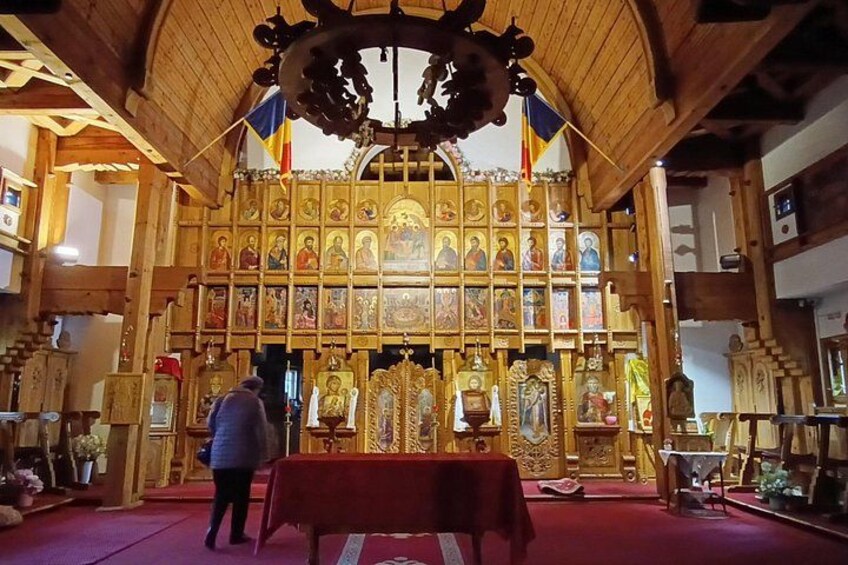 A church interior with a wooden altar, religious icons, and a red carpet. 2