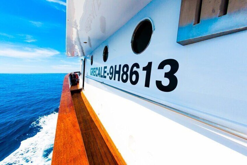 A boat with the number 9H8613 on its side, wooden deck, and the ocean in the background. 5