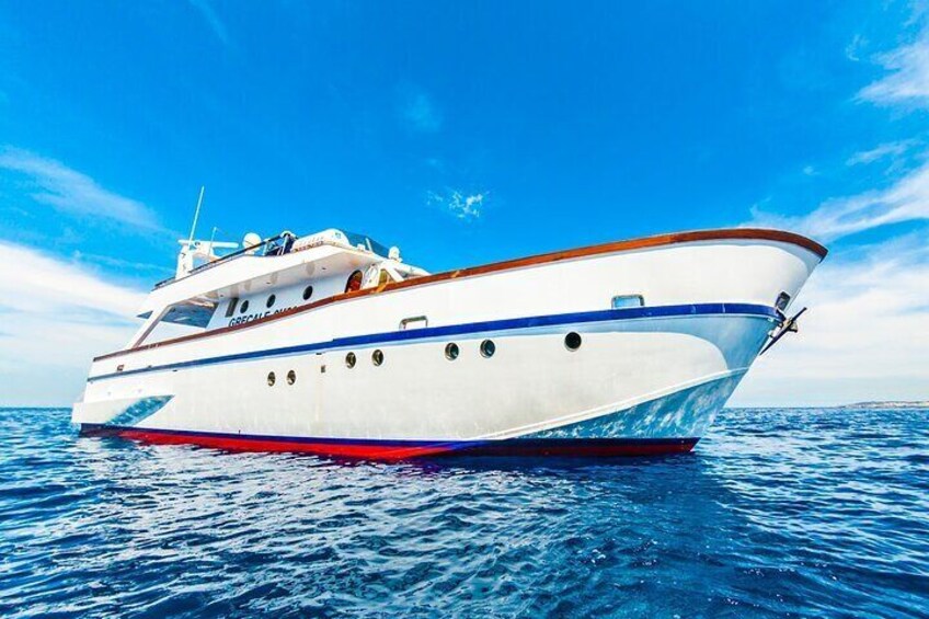 A white yacht with blue and red trim sailing on blue water. 3