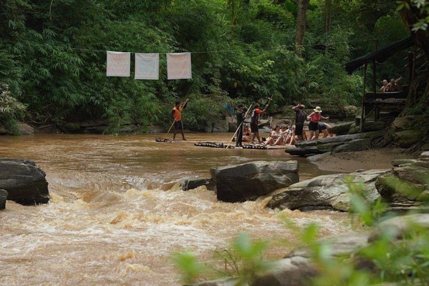 A river with people paddling in boats, surrounded by dense greenery and rocks. 5