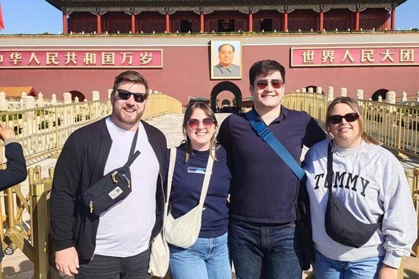 Eine Gruppe von Personen steht vor einem Gebäude mit einem großen Porträt und chinesischen Schriftzeichen. 1