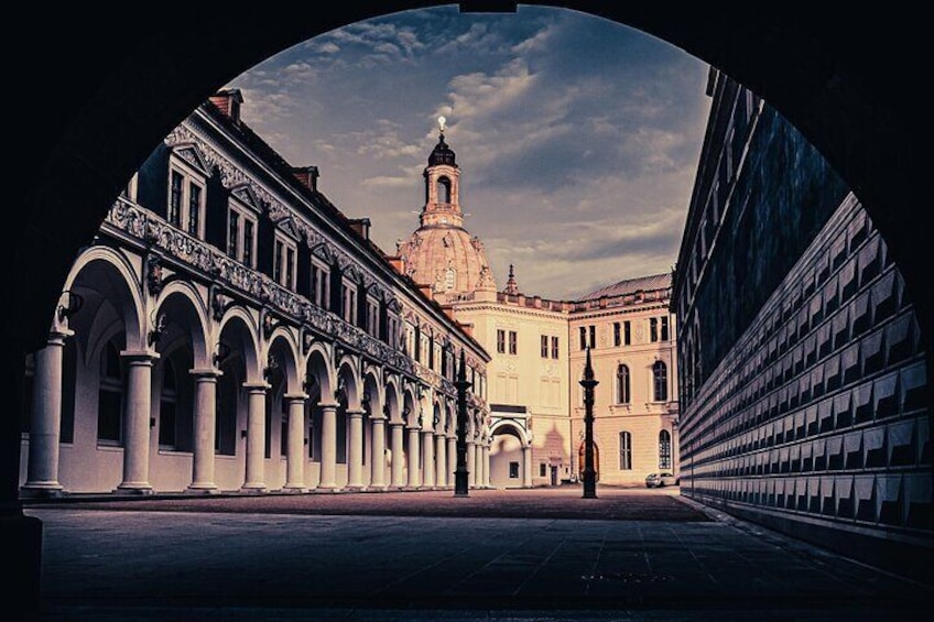 A historical building with arched walkways and a prominent tower. 3