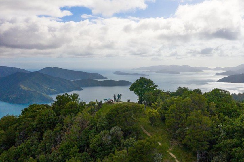 A mountainous landscape with a lake, a path, and a group of people standing on a hill. 1