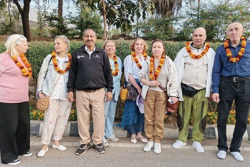 A group of people standing outdoors, some wearing leis. 1