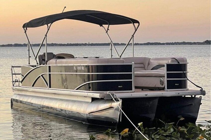 A pontoon boat with a canopy, seating, and a motor. 4
