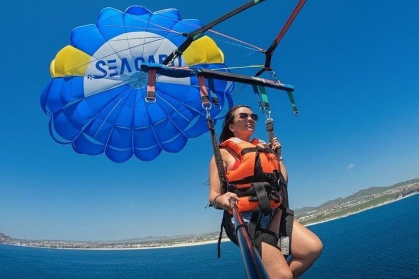 A person parasailing over a body of water with a clear sky. 1