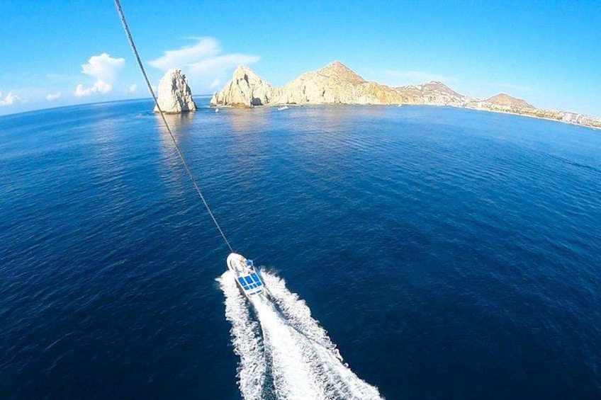 A boat moving through a calm sea with a clear sky, rocky islands, and a distant mountain range. 4