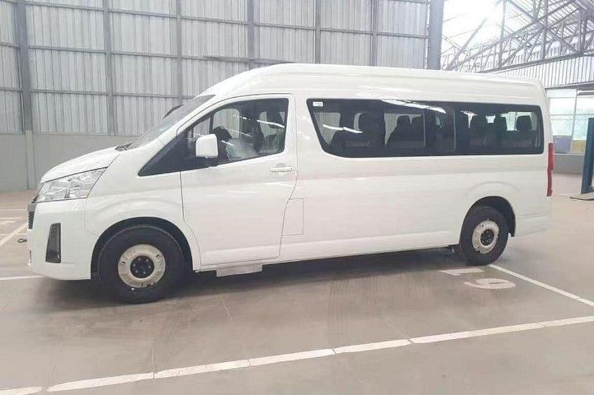 A white van parked inside a building with a large industrial structure in the background. 3