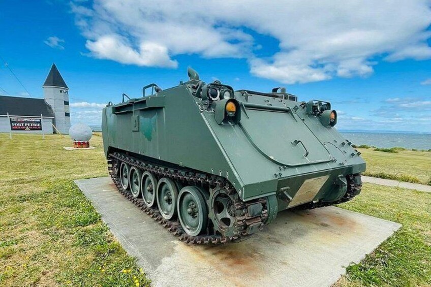 A military vehicle with tracks, a turret, and a mounted gun, parked on a concrete pad. 3